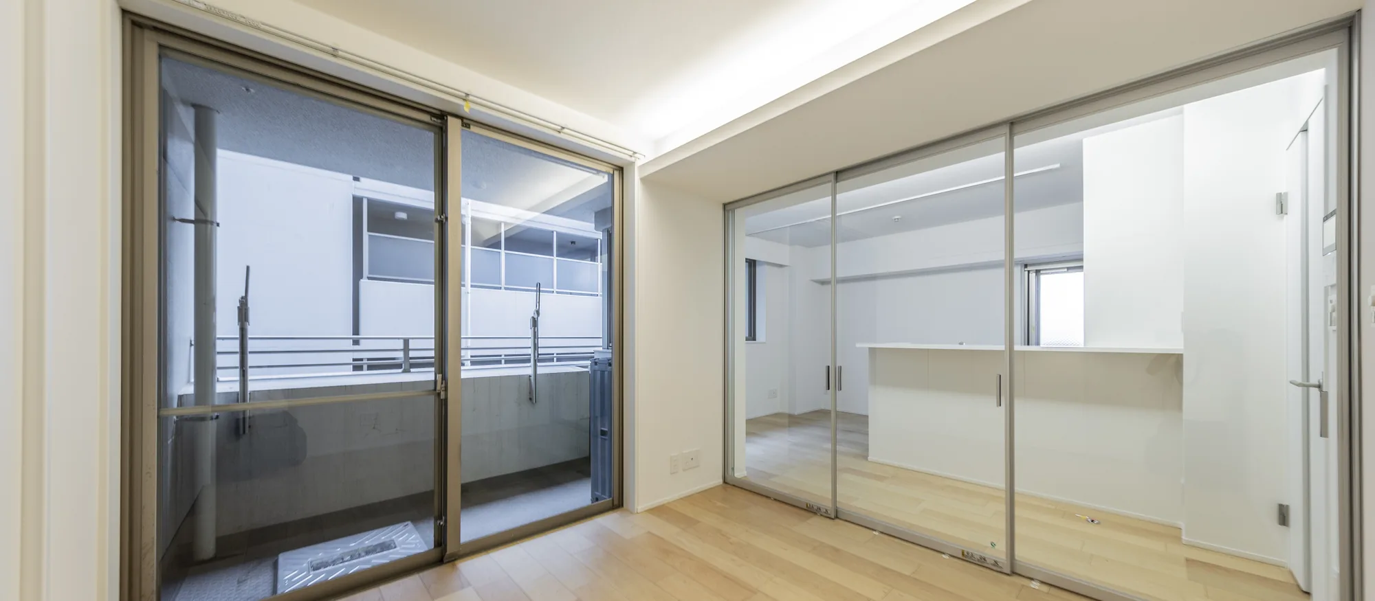 白い部屋に、ガラスの間仕切り｜墨田区のマンションフルリノベーション事例のLDK